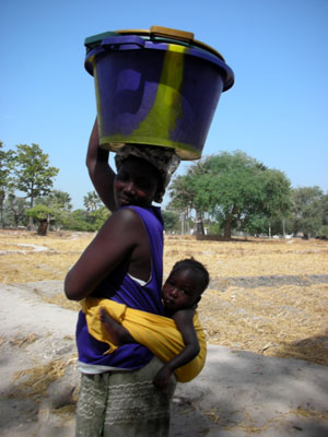 Senegalese mother and child returning to village with potable water 